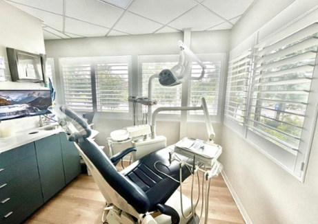 Dental office interior with a modern chair, dental equipment, and a large window.