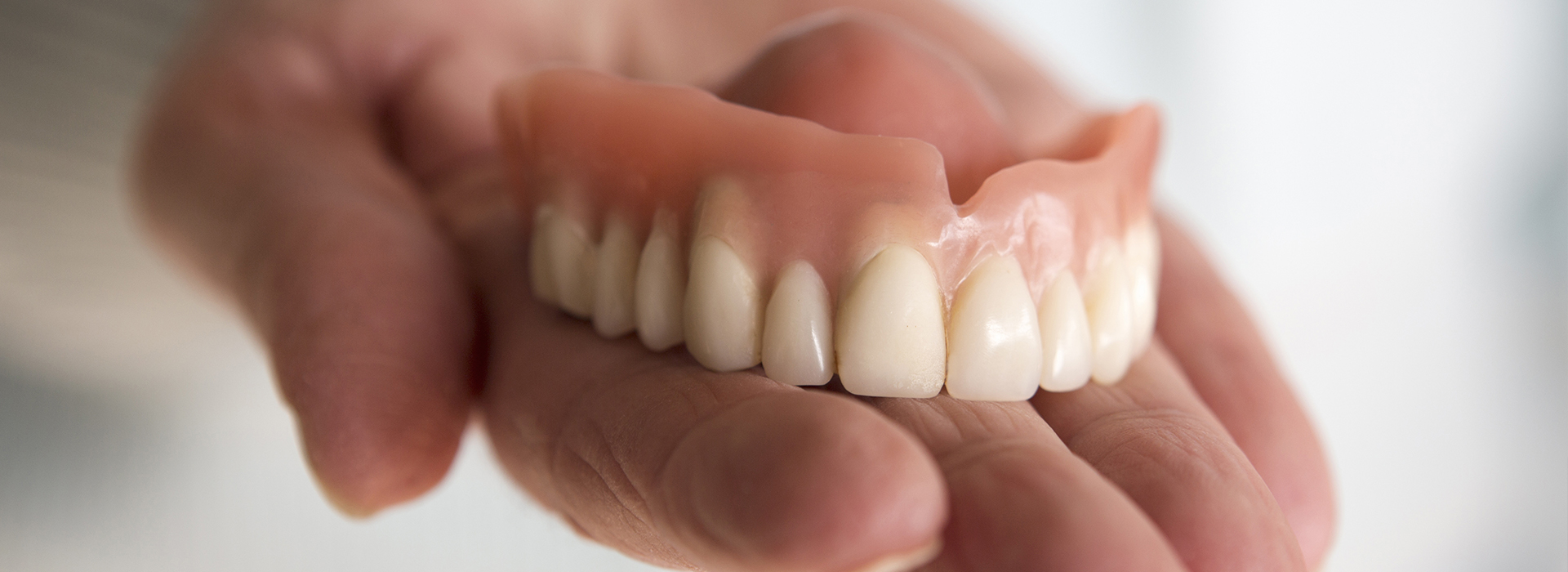A hand holding a set of dentures.